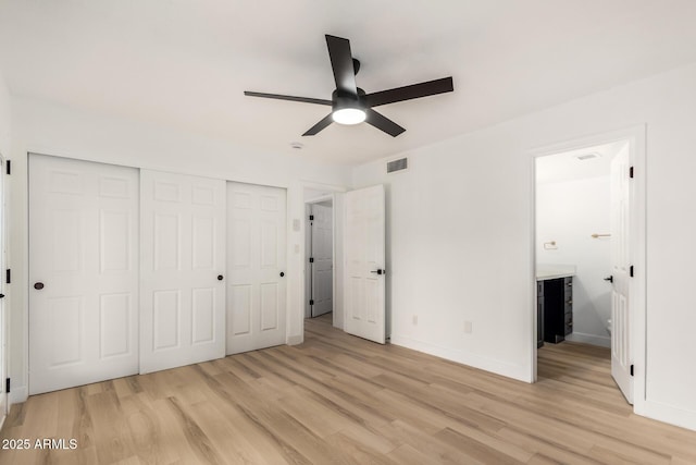 unfurnished bedroom with ensuite bathroom, light wood-style flooring, visible vents, baseboards, and a closet