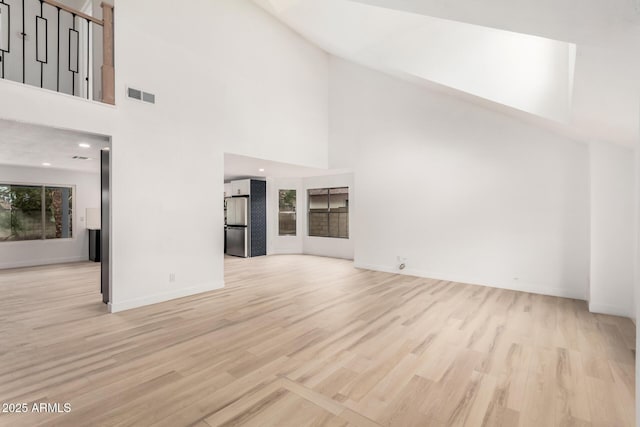 unfurnished living room featuring baseboards, visible vents, wood finished floors, high vaulted ceiling, and recessed lighting