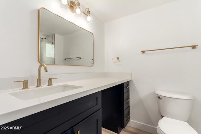 bathroom with wood finished floors, vanity, toilet, and baseboards