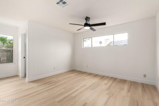 unfurnished room featuring light wood-style floors, visible vents, and baseboards