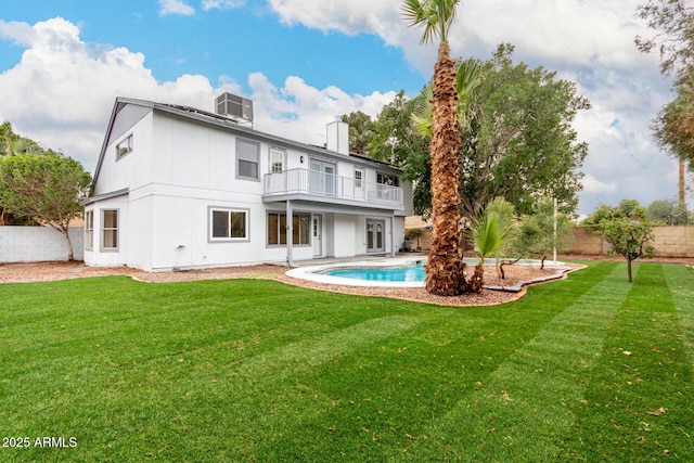 rear view of house featuring central AC unit, a fenced backyard, a balcony, a lawn, and a fenced in pool