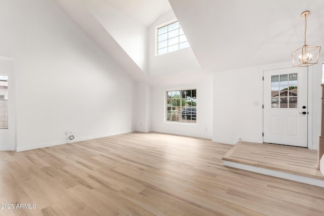 unfurnished living room with a healthy amount of sunlight, a notable chandelier, and light wood-style flooring