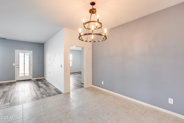 empty room with a chandelier and light tile patterned floors