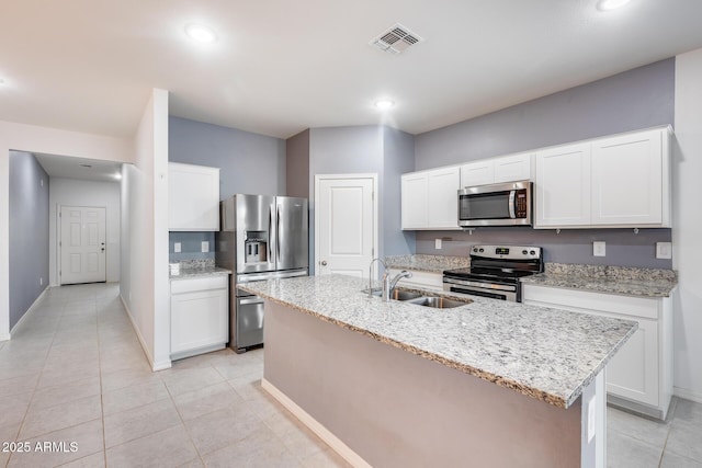 kitchen featuring sink, white cabinets, a kitchen island with sink, light stone counters, and stainless steel appliances