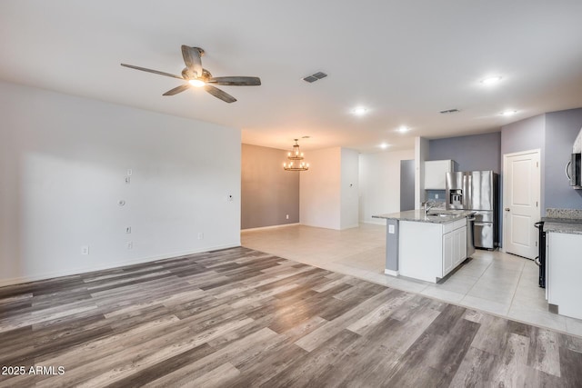 kitchen with sink, a center island with sink, stainless steel appliances, light stone countertops, and white cabinets