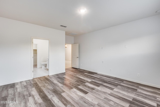 unfurnished bedroom featuring ensuite bathroom and light hardwood / wood-style floors