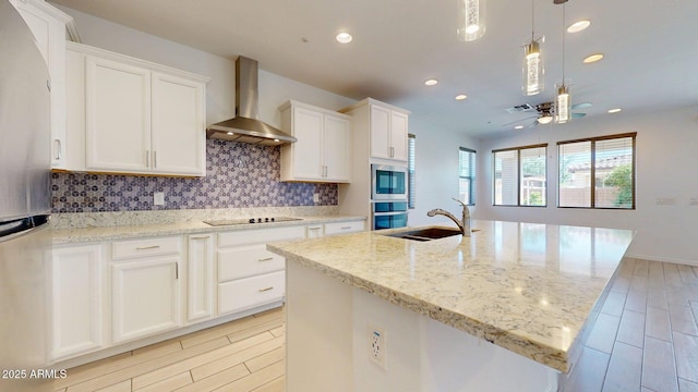 kitchen with wall chimney range hood, recessed lighting, tasteful backsplash, a sink, and stainless steel appliances