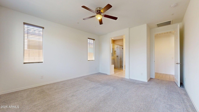 unfurnished bedroom with visible vents, baseboards, ensuite bathroom, ceiling fan, and light colored carpet