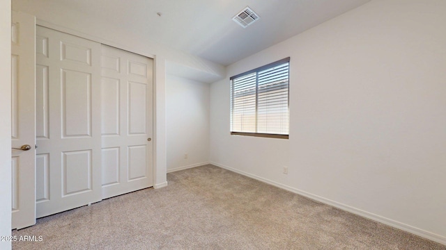 unfurnished bedroom with baseboards, visible vents, light carpet, and a closet