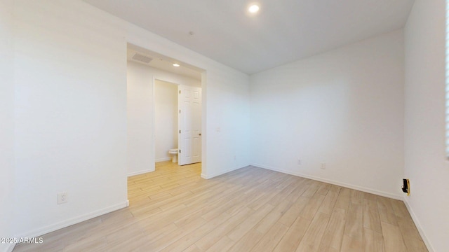 empty room featuring light wood-style floors, baseboards, recessed lighting, and visible vents