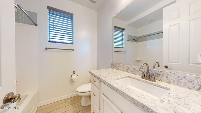 bathroom featuring shower / tub combination, wood finished floors, baseboards, vanity, and toilet