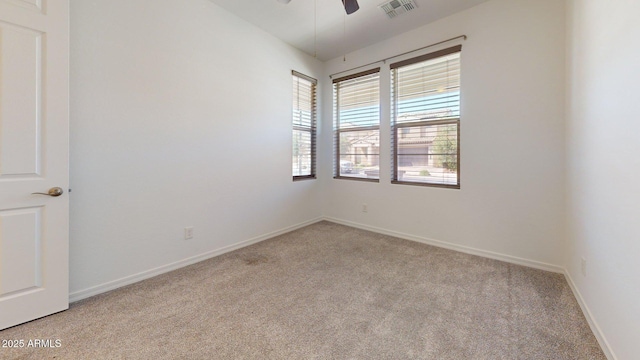 spare room with a ceiling fan, baseboards, visible vents, and light carpet