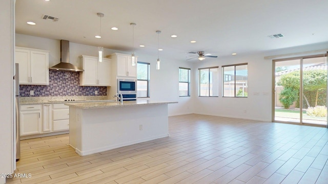 kitchen featuring black electric stovetop, wall chimney exhaust hood, recessed lighting, tasteful backsplash, and visible vents