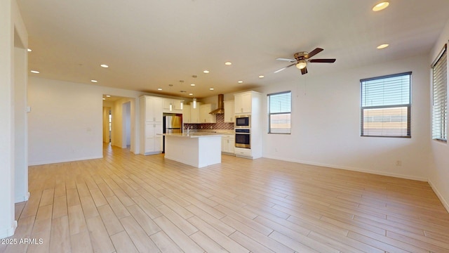 unfurnished living room featuring baseboards, ceiling fan, recessed lighting, and light wood-style flooring