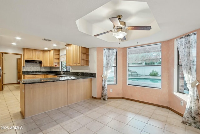 kitchen featuring sink, tasteful backsplash, light tile patterned floors, kitchen peninsula, and dark stone counters