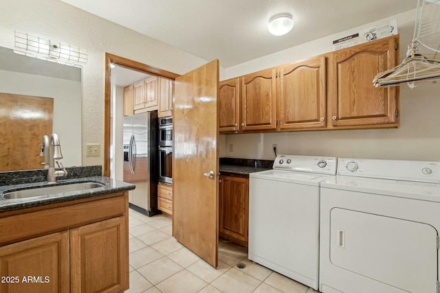 clothes washing area with independent washer and dryer, cabinets, light tile patterned flooring, and sink