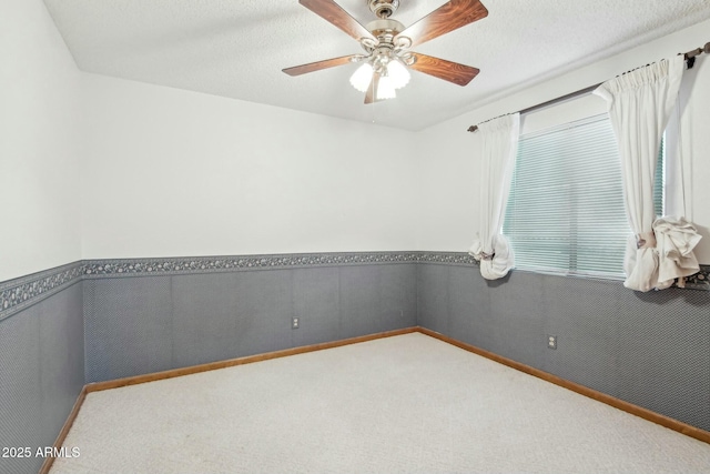 empty room featuring light carpet, ceiling fan, and a textured ceiling