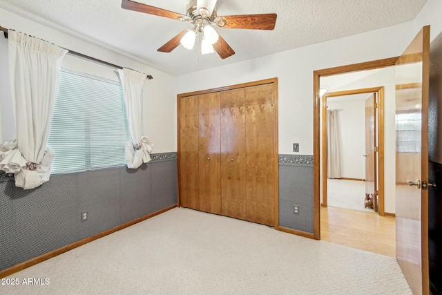 carpeted bedroom with ceiling fan, a closet, and a textured ceiling