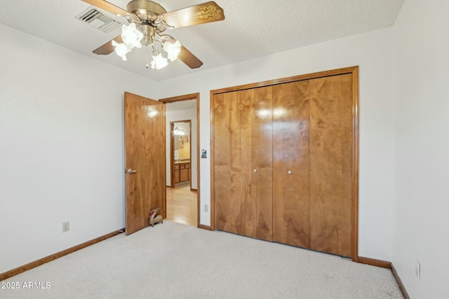 unfurnished bedroom featuring ceiling fan, a closet, light carpet, and a textured ceiling