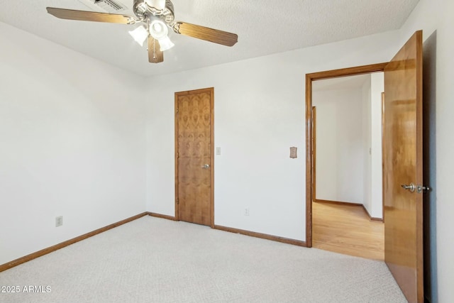 unfurnished bedroom featuring ceiling fan, light colored carpet, and a textured ceiling