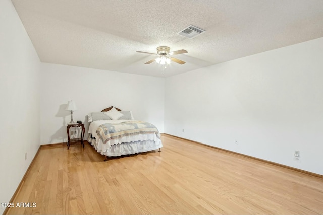 bedroom featuring ceiling fan, a textured ceiling, and light hardwood / wood-style floors