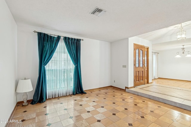 tiled foyer entrance featuring lofted ceiling, a notable chandelier, and a textured ceiling