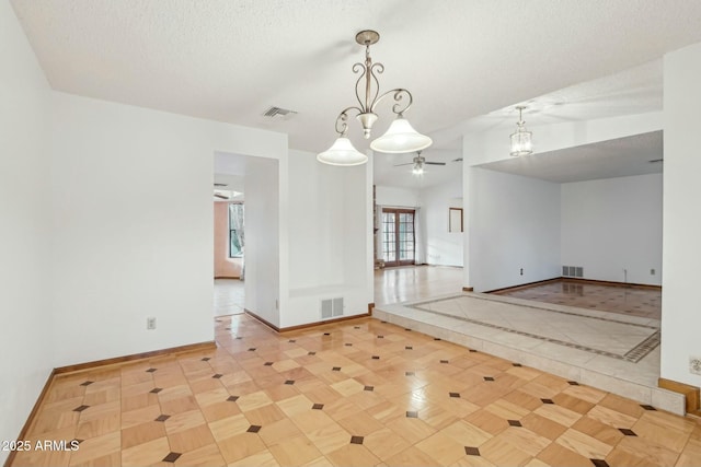 unfurnished room with ceiling fan with notable chandelier, light parquet flooring, and a textured ceiling