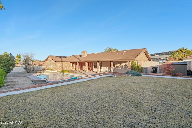 rear view of house with central AC, a patio, and a lawn