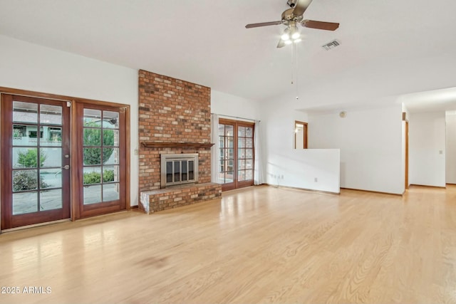 unfurnished living room with ceiling fan, a fireplace, light hardwood / wood-style floors, and french doors