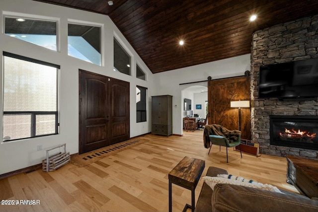 foyer with light wood finished floors, a barn door, and high vaulted ceiling