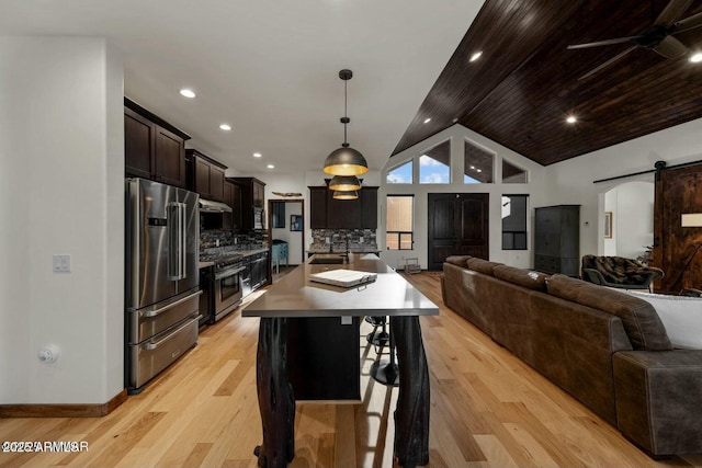 kitchen with a breakfast bar, a barn door, open floor plan, an island with sink, and high quality appliances