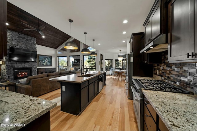 kitchen featuring a kitchen island with sink, under cabinet range hood, stainless steel appliances, a sink, and open floor plan