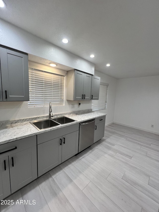 kitchen with sink, stainless steel dishwasher, light hardwood / wood-style floors, and gray cabinetry