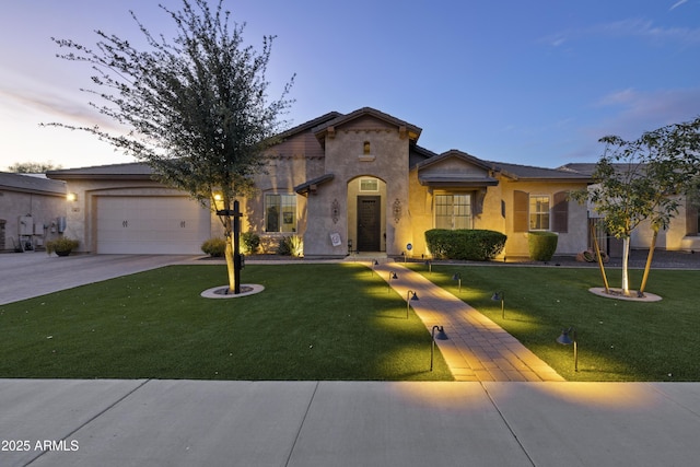 mediterranean / spanish house featuring a garage, driveway, a lawn, and stucco siding