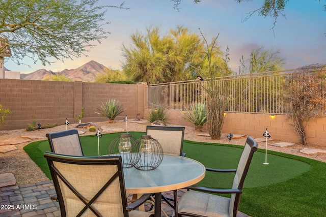 patio terrace at dusk featuring a mountain view and a fenced backyard