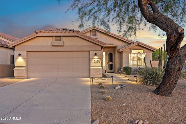 view of front of house with stucco siding, a tiled roof, driveway, and an attached garage