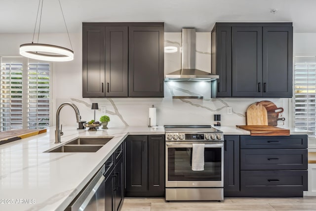kitchen with appliances with stainless steel finishes, a sink, a wealth of natural light, and wall chimney exhaust hood