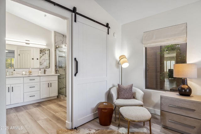 living area with light wood-style flooring, vaulted ceiling, and a barn door