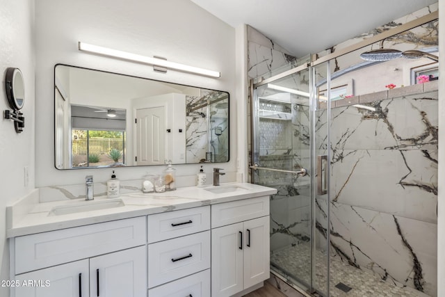 bathroom with a marble finish shower, a sink, and double vanity