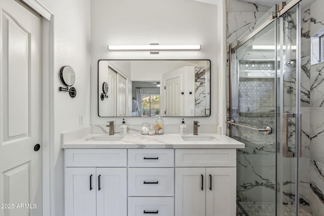 bathroom with a marble finish shower, double vanity, and a sink