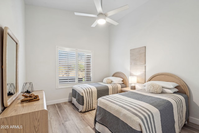bedroom with light wood finished floors, a ceiling fan, high vaulted ceiling, and baseboards
