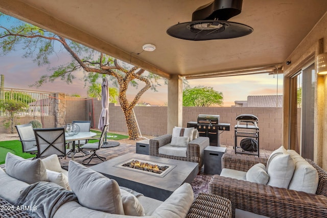 patio terrace at dusk featuring an outdoor living space with a fire pit, area for grilling, outdoor dining space, and a fenced backyard