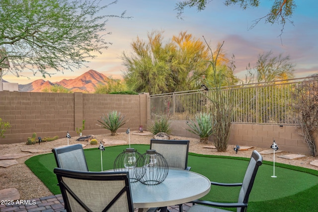 patio terrace at dusk featuring a fenced backyard