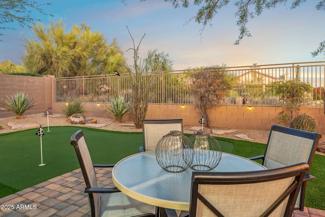 patio terrace at dusk featuring outdoor dining area and a fenced backyard