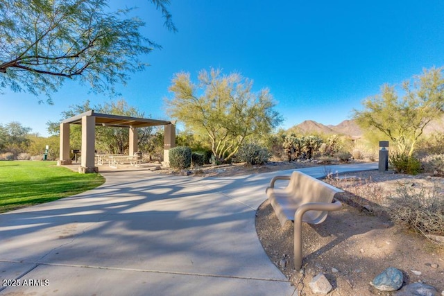 view of home's community featuring a lawn, a patio area, and a mountain view