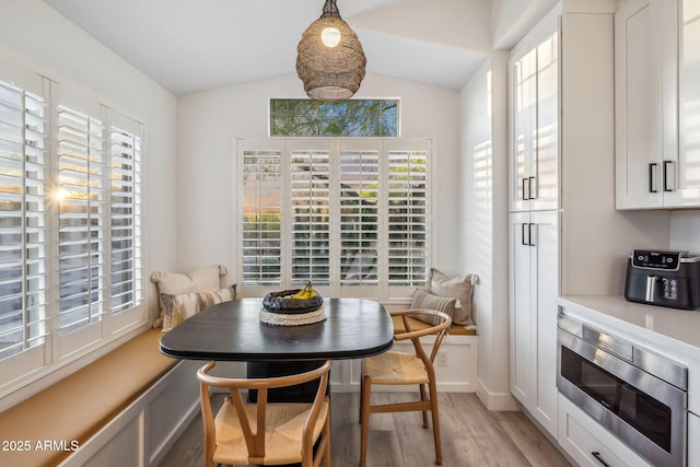 dining area with lofted ceiling, light wood-type flooring, breakfast area, and baseboards