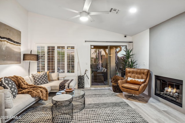 living room with wood finished floors, a wealth of natural light, ceiling fan, visible vents, and lofted ceiling