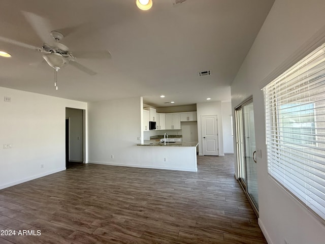 unfurnished living room with ceiling fan, sink, and dark wood-type flooring