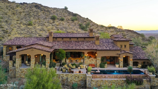 back house at dusk with a mountain view and a patio