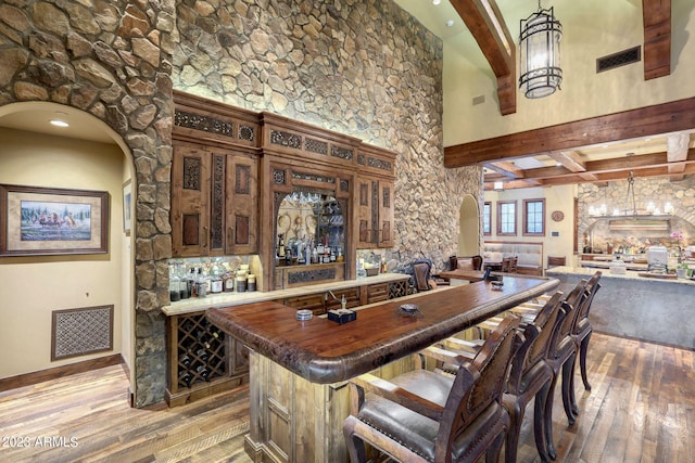 interior space with dark wood-type flooring, a towering ceiling, pendant lighting, butcher block countertops, and beam ceiling